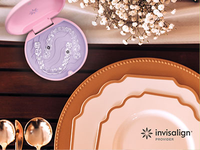 A photograph of a table setting with various plates, a cake server, and a box of dental implants in the background.