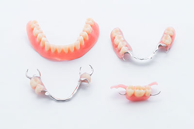 The image displays a collection of dentures, including upper and lower sets with teeth, arranged on a white surface.