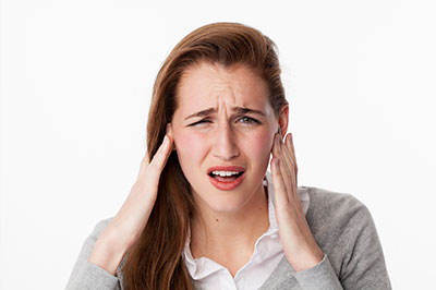 A woman with her hand on her head, appearing concerned or in pain.