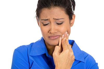 A woman with a concerned expression, holding her nose and looking upwards.