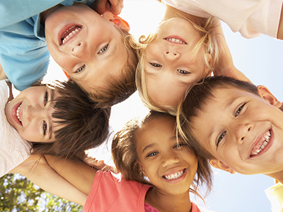 Children happily posing for a group photo outdoors.